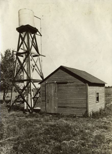Small wooden building next to a tall water tower.