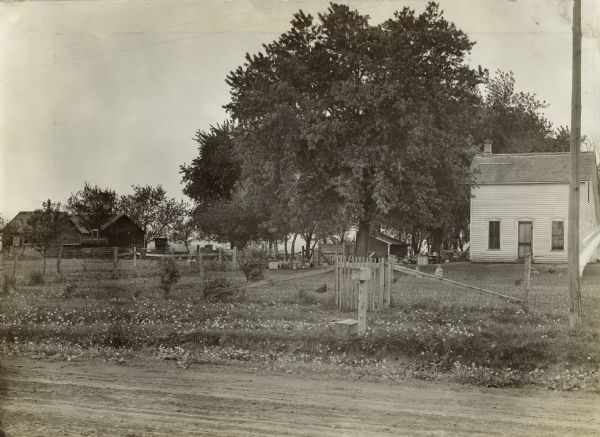 Farm yard and buildings as seen from a rural road. Original caption: "This farm has been farmed by tenant for at least 10 years. Present tenant J.T. Siebel who had rented it five years. Photograph was taken by turning camera around but not moving it from spot after taking photograph of D.G. Lichty farm across the road (5103). Note farm machinery left without protection. Note absence of Silo. Picture ordered by E.W. Cooley. Plate in possession Flint's Studio, Waterloo, Iowa."