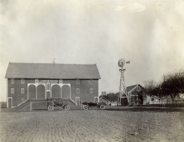 Barn labeled: "John W. Hoover Maple Farm, 1892." In front of the barn are two automobiles and a field. Next to the barn is a windmill and other farm buildings.