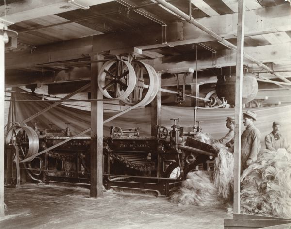 Men feed sisal fiber into a combing machine during the production of binder twine at the McCormick Twine Mill.