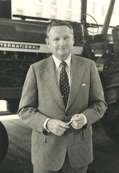 Three-quarter length portrait of Frank R. Milnor standing in front of an International Harvester tractor. He spent 43 years working for the company, eventually becoming a Vice President and Treasurer.