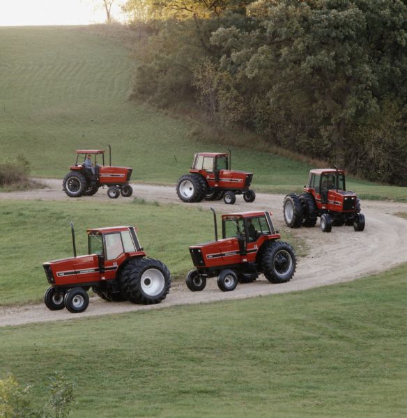 Color photograph of five tractors from International Harvester's "50 Series" on a hillside dirt road.