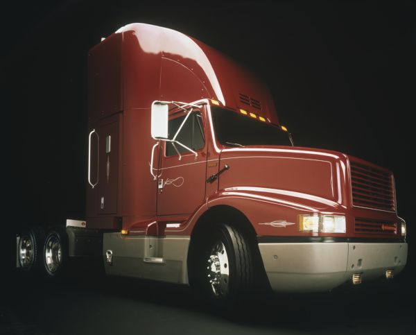 Three-quarter side view color photograph of an International 8300 semi-truck (tractor) in a studio with a black background.