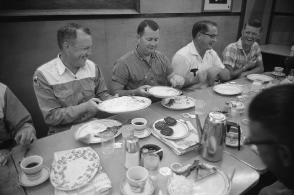 International Harvester salesmen gather at a table to share a meal at the company farm at Tifton. International Harvester offered classes on the farm in order to provide its sales force with hands-on experience with agricultural equipment in the field.