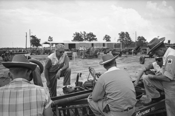 Instructor Jim Brosnahan (left, with foot on plow) gathers around a Kewaunee plow with International Harvester employees to study it at an International Harvester company farm in Tifton. International Harvester offered classes on the farm in order to provide its sales force with hands-on experience with agricultural equipment in the field.