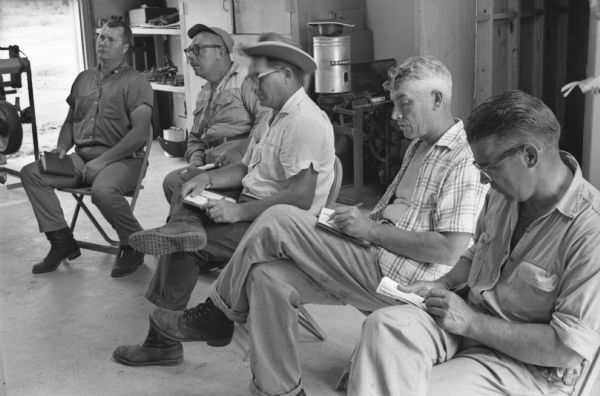 International Harvester employees sit in folding chairs while taking notes inside a building on the company's training farm at Tifton. International Harvester offered classes on the farm in order to provide its sales force with hands-on experience with agricultural equipment in the field.