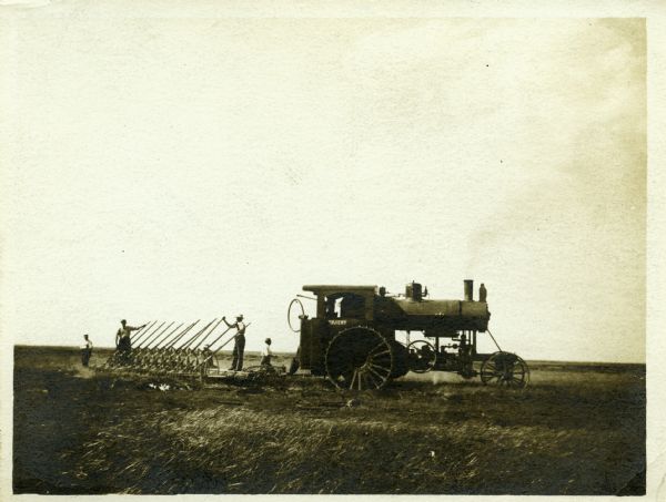 Men use an Avery 130 tractor with a gang plow to work in a farm field.