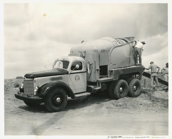Men from the Gethmann Concrete & Material Company use a Ready-Mix concrete mixer on the chassis of an International KB-8 truck.