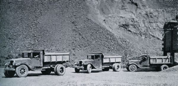 Three International trucks lined up on the construction site of the Grand Coulee Dam.
