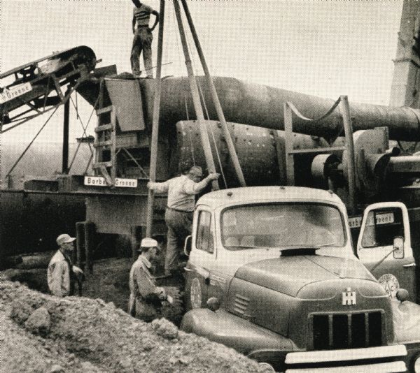 Men use an International R-194 to perform tasks on a highway construction site.