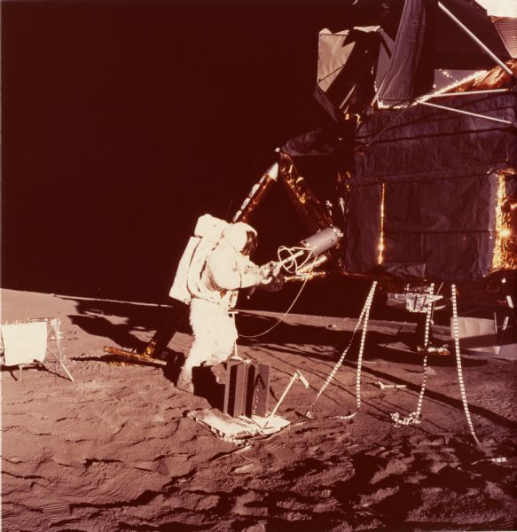 An Apollo 12 astronaut and lunar landing module on the moon's surface. The beryllium container in the foreground was built by the Solar Division of International Harvester, and was used to power instruments on the moon.