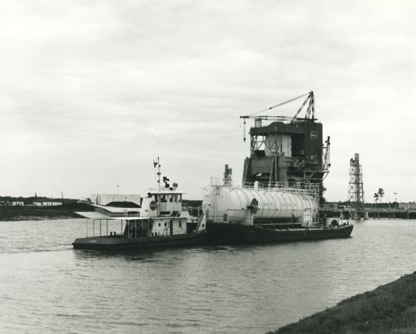 NASA towboat, the "Clermont", pulling a liquid oxygen tank in the canal system of the Mississippi Test Support Department. Original caption reads (in part): "A Solar Saturn gas turbine engine provides power to generate electricity for two 423-horsepower electric motors for NASA's towboat."