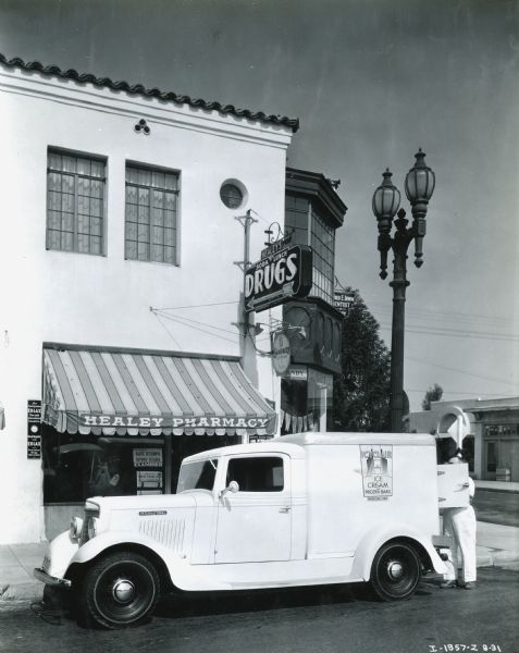 A man unloads ice cream bars from the back of an International C-1 truck while making a delivery to Healey's Pharmacy.