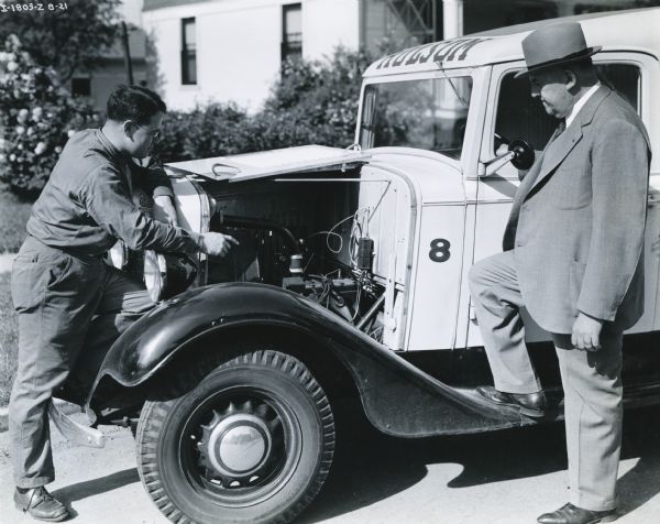 Frank H. Rolfes (right), president of the Springfield Ohio Baking Company and driver of the International Model C-5 truck, stands next to the truck as another man inspects its inner workings. Painted on the front of the roof of the truck is the word: "Holsum".