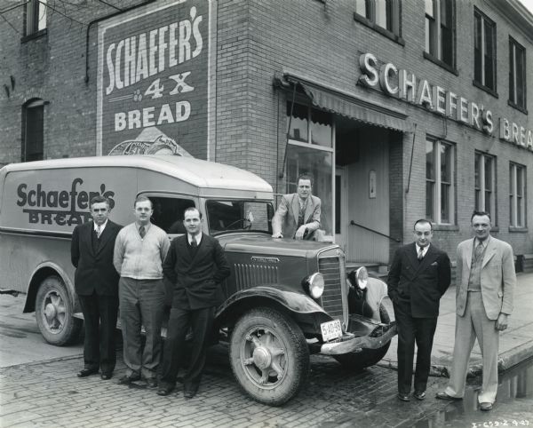 A group of men pose with an International truck owned by Schaefer's Baking Company outside the company factory.
