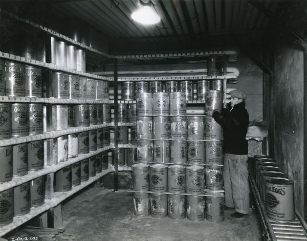 A man stacks metal storage containers inside a refrigerator storage room at Washington Co-operative Egg & Poultry Association.