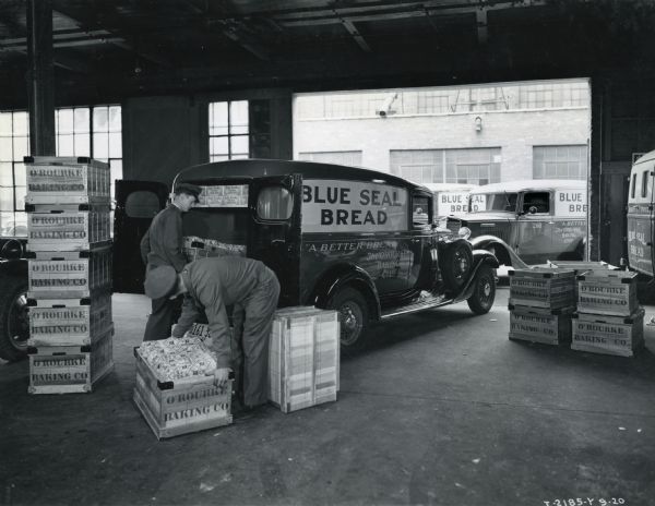 Men inside building load an International Model C-1 truck with crates of bread from O'Rourke Baking Company.