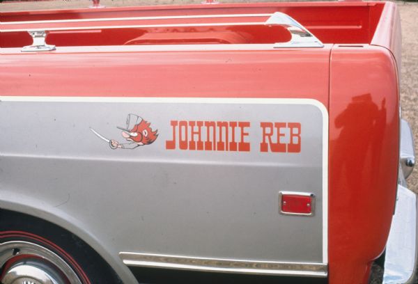 Close-up color photograph of the rear corner of a "Johnnie Reb" truck taken by the International Harvester Styling Department. Includes the "Johnnie Reb" name and a caricature of a Confederate soldier wielding a sword. The reflection of the photographer is visible in the back corner of the truck.
