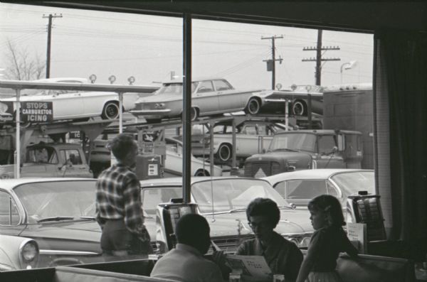 A table of customers looks over the menu at the diner in a Mt. Victory truck stop. The caption on a similar photograph reads: "Service to a 'T' awaits drivers in a hurry at the special trucker counter. Stamping a red 'T' to orders gets the fastest service possible."
