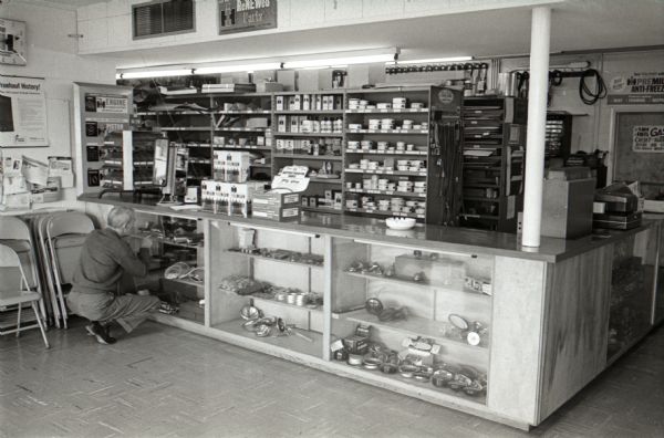 A man bends down and points at International Harvester parts on display as a clerk looks on at the Mt. Victory truck stop, or service plaza.