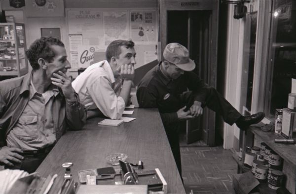 Three men, probably truck drivers, gather at the service counter at the Mt. Victory truck stop.