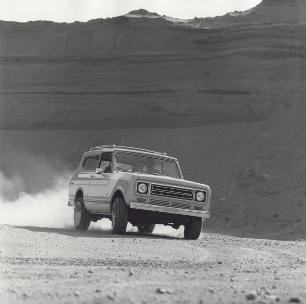 A man is driving an International Scout II in what appears to be the southwest United States.