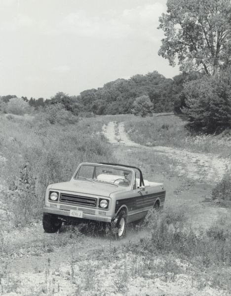 A man is driving an International Scout Terra on a dirt road. Photograph was taken for International Harvester by Brandt & Assoc., Ltd. Photography of  Barrington Hills, Illinois.