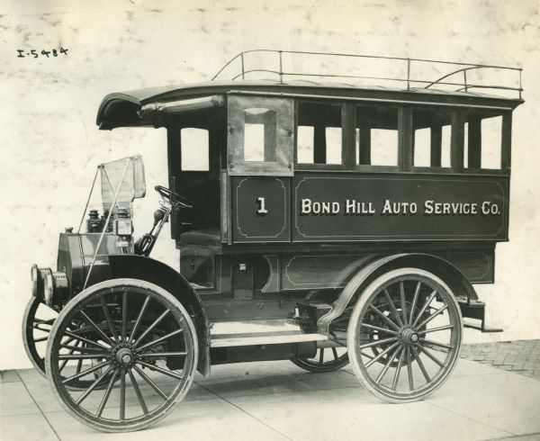 Three-quarter view from front of left side of an International bus used by the Bond Hill Auto Service Co. There is a luggage rack on the roof.