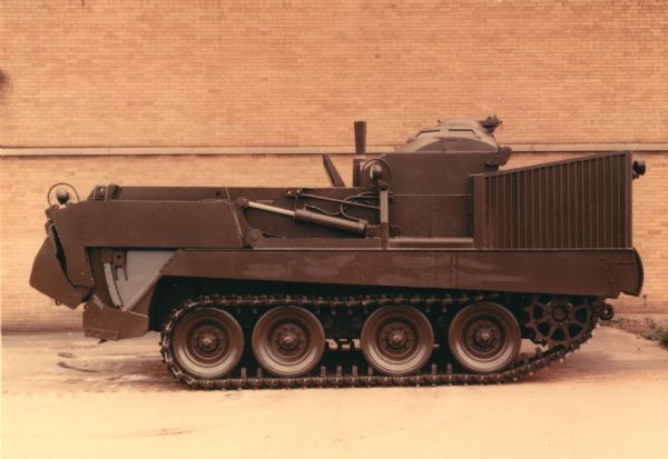 Color photo of the Universal Engineer Armored Tractor. This vehicle provides the United States Army, Corps of Engineers, with protected mobility and support capacity for the Combat Engineer Squad, ability to accompany and support fast moving armored columns under any terrain condition, a machine which possesses the same land and water mobility and armored protection as does the armored personnel carrier, a self-loading tractor that operates as a bulldozer, scraper, and dump truck, and an air transportable unit.