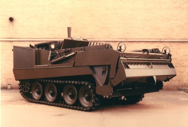 Color photo of the Universal Engineer Tractor. The original caption reads: "Ready for combat — by land or water, and air transportable, the UET-E1 (Armored) can travel at 30 mph, permitting it to maintain speed with any armored column. It can move personnel, dirt, and cargo in quantity and in a hurry; tractive ability equal to large construction tractors is available instantly. Watch the UET-E1 in action in the pictures that follow and see for yourself."