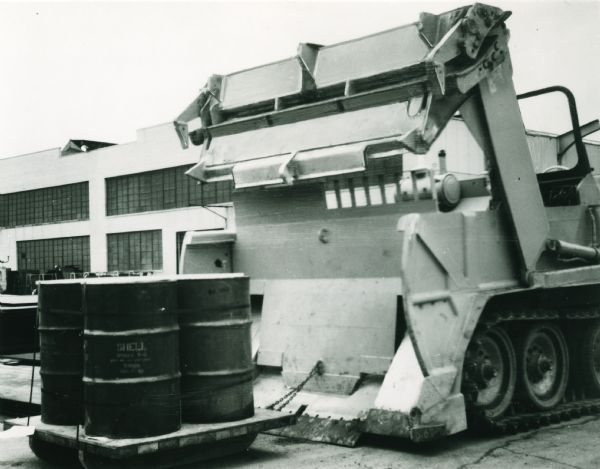 The original caption reads: "Palleted cargoes can be loaded and unloaded by attaching the pallet to the eye located in the center lower area of the ejector. As the ejector moves to the rear, the pallet is pulled easily into the tractor. To remove the load, the ejector simply is moved forward after the apron is raised. Again, the Universal Engineer Tractor (Armored) reduces the need for other types of mobile equipment."