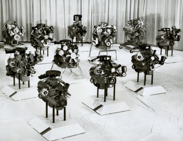 Showroom of International Harvester engines for their truck lines. Original caption reads: "Photo #TF-1244- Parade of Power. International Harvester produces a complete line of truck engines — both gasoline and diesel. These range from the four-cylinder, 196 cubic inch gasoline engine for Scout vehicles to the 350-hp version of the bit-bore V800 diesel. Engines displayed here include the 4-196, the V-345, V-392, MV-404, MV-446, V-537, and V-605--all gasoline units; and the DT-466, and V-800 models. TD-3832."
