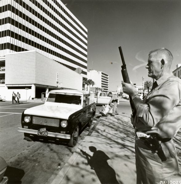 International Harvester Scout. Original caption reads: "Saving Pennies while It Caries Millions. Photograph No. MX-10029-- A David doing work normally reserved for Goliaths is this compact vehicle of Armored Car, Inc., at Tucson, Ariz. Heavy armor plate and one-inch-thick bullet resistant windows turn the perky Scout by International into a rolling fortress — at times a transporter of millions in cash. Armored's progressive president, Baker Hardin, says his firm's highly maneuverable Scouts — it has three — are fully as unassailable as larger armored cars, while their low cost and 4 cyl. engines have introduced a convincing new economy feature to the armored car field. MT-2806. CR-1146-D."