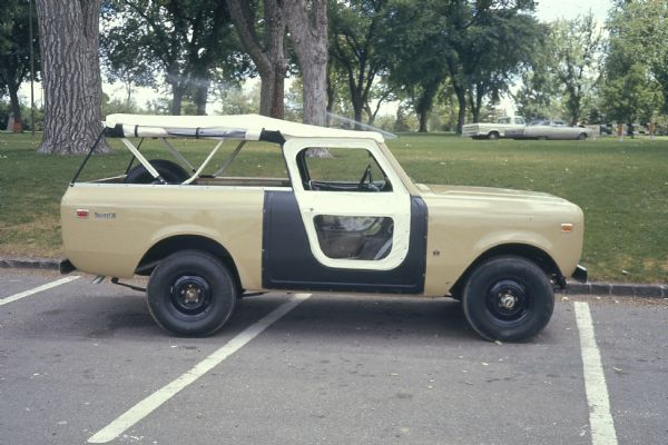 Side view of passenger side of Scout II in a parking lot near trees and grass (possibly a park).