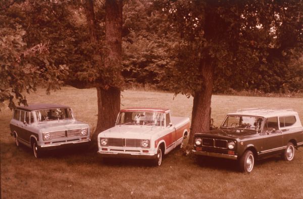 Three Scouts parked under two trees outdoors.