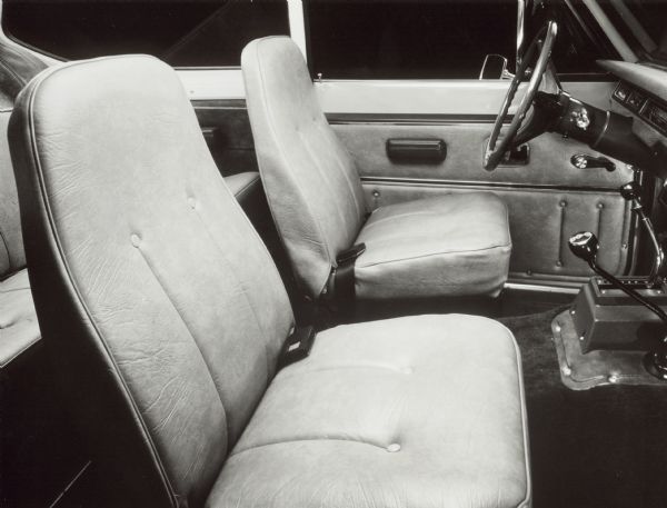 Original caption reads: "photo #tf-1205. 1975 International Scout interior features five new color combinations and a custom package in fabric and vinyl. This includes: molded, color-keyed vinyl soft trim for rear quarter panels in cargo area; spare tire cover and vinyl cargo mat and color-keyed to interior; wood grain inserts for door panels; wood grain instrument panel insert; color-keyed horn pad; carpeted kick panels and a wood grain insert on automatic transmission shift console. TD-3763a 10/1/74."