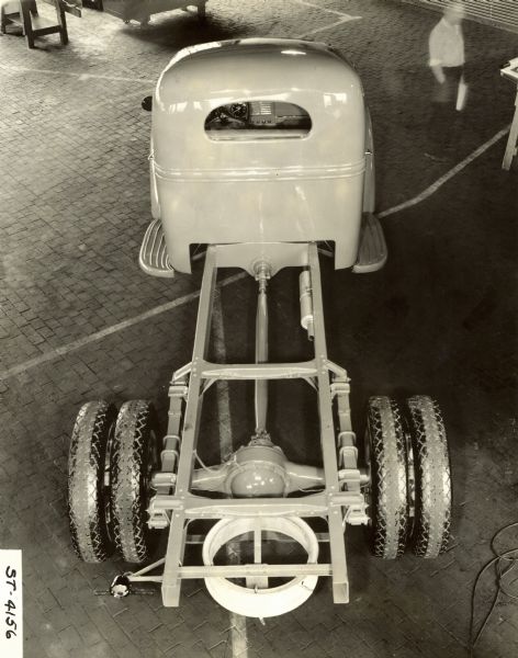 Elevated view of an International Harvester truck model chassis and cab. A man is walking in the background on the right. Possibly a Raymond Loewy design.