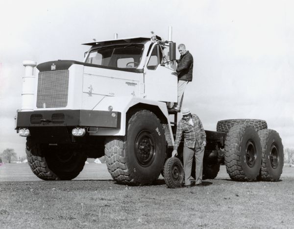 Original caption reads "Current Model -- The wheel of a Scout is dwarfed by that of an International truck tractor recently sold to the National Aeronautics and Space Administration. The 32,000 lb giant is being used at Cape Kennedy to haul away the masses of gantry "slag" resulting from rocket blast-offs. 1/12/66."