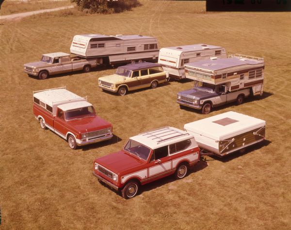 Elevated view of five Scouts parked in a field. Four of the Scouts are attached to trailer campers and RVs. In the foreground is a Scout II.