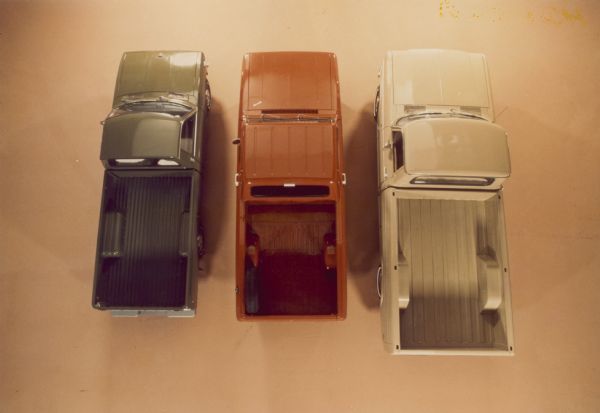 Overhead view of three Scouts. From left: green, orange, tan Scouts with open truck beds. The Scout in the middle has a spare tire mounted on the side of the truck bed.