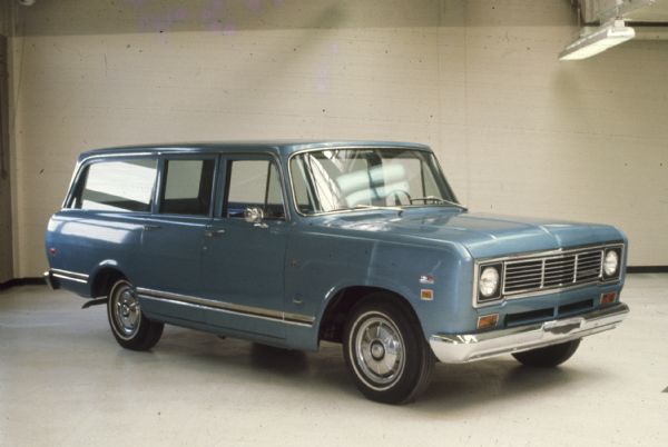 Three-quarter view from front of passenger side of blue 4-door Scout parked indoors.