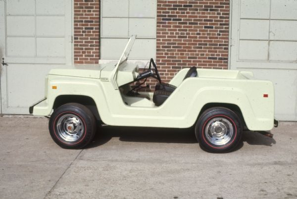 Driver's side view of white Scout parked outdoors in front of a brick building.