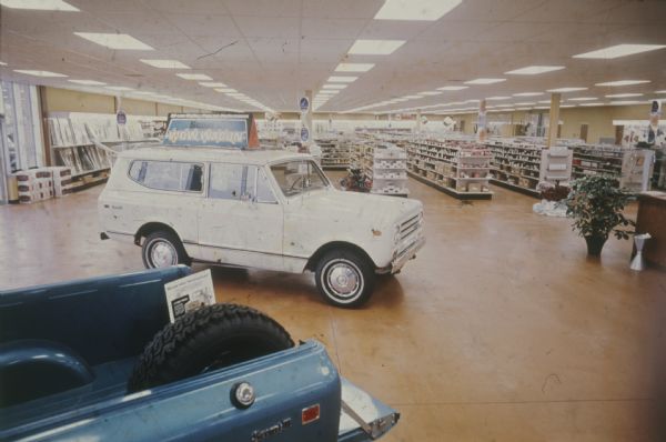 Blue Scout II, and white Scout II with a "WOW Wagon" sign, parked indoors on showroom floor. Shelves of merchandise are visible in the background.