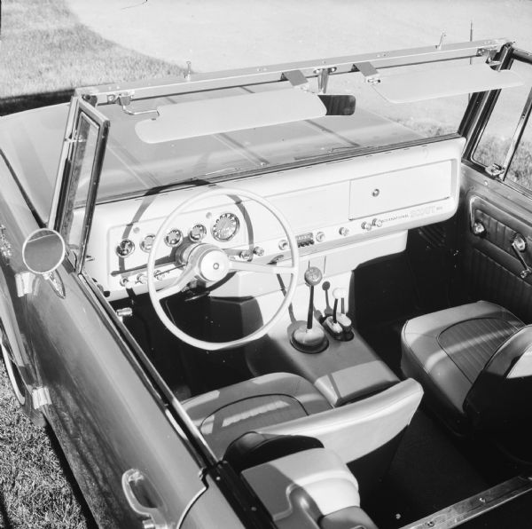 View looking down at interior of driver's side of International Scout 800 parked outdoors on the grass.
