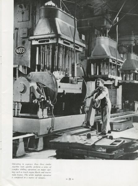 A man is running a machine tool at a International Harvester factory in Australia. Machine name, "NATCO," is on a plate attached to the machinery.