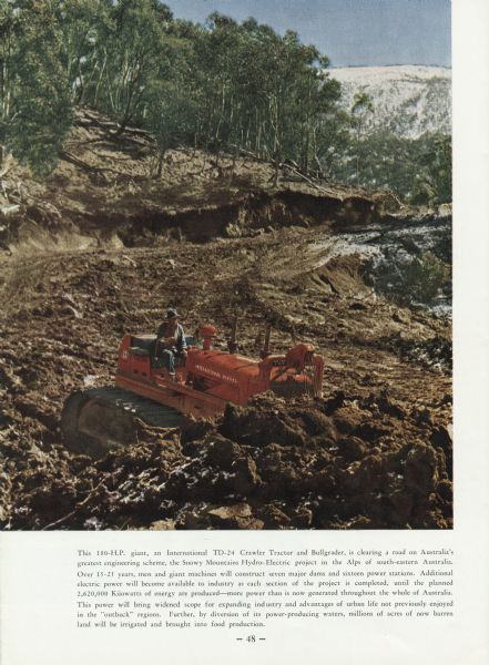 A TD-24 Tractor and bullgrader seen clearing a road. A man is seen driving tractor pushing dirt out of the way. Original caption reads: "This 180-H.P. giant, an International TD-24 Crawler Tractor and Bullgrader, is clearing a road on Australia's greatest engineering scheme, the Snowy Mountains Hydro-Electric project in the Alps of south-eastern Australia. Over 15-25 years, men and giant machines will construct seven major dams and sixteen power stations. Additional electric power will become available to industry as each section of the project is completed, until the planned 2,620,000 Kiiowatts of energy are produced, more power than is now generated throughout the whole of Australia. This power will bring widened scope for expanding industry and advantages of urban life not previously enjoyed in the "outback" regions. Further, by diversion of its power-producing waters, millions of acres of now barren land will be irrigated and brought into food production."