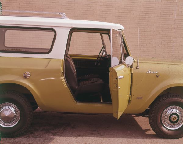 Passenger side view of yellow Scout with white topper. Passenger side door is open to show the front seat.