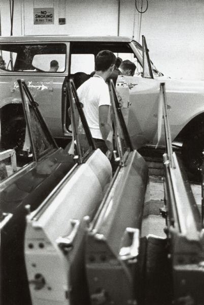 Men working on the Fort Wayne production line. They are investigating the inside of an International Scout at the door assembly portion of the Fort Wayne plant.
