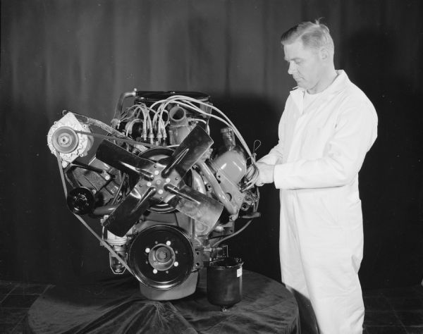 Man standing near Scout engine displayed on table draped with fabric.