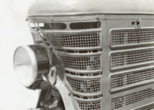 Close-up of a F-22 International Harvester tractor with a headlight attachment. One headlight is seen on the front grill of the a tractor. The original caption reads: "F-22 with lighting attachment."